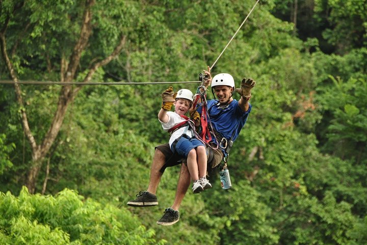 Two kids on the zipline canopy tour over the rainforest near Jaco, Costa Rica