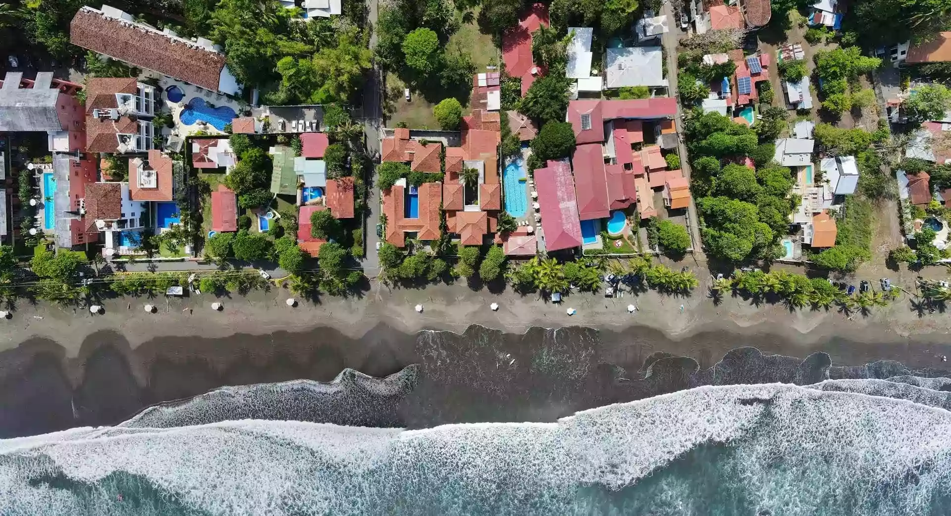 Aerial drone view of beachfront accommodations and coastline in Jaco Beach, Costa Rica