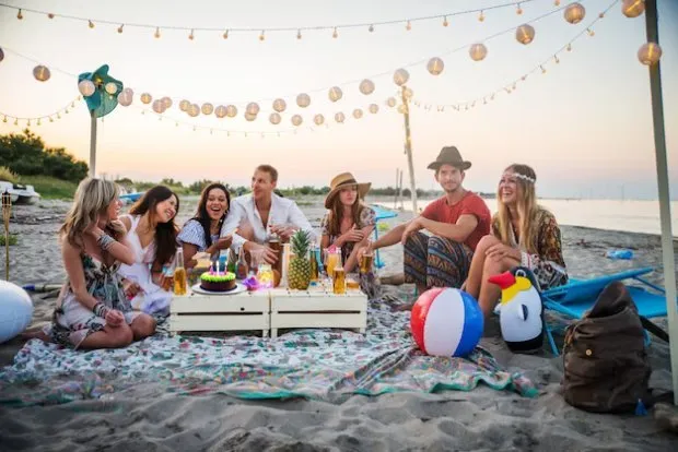 Friends celebrating with a picnic under string lights on a Costa Rica beach