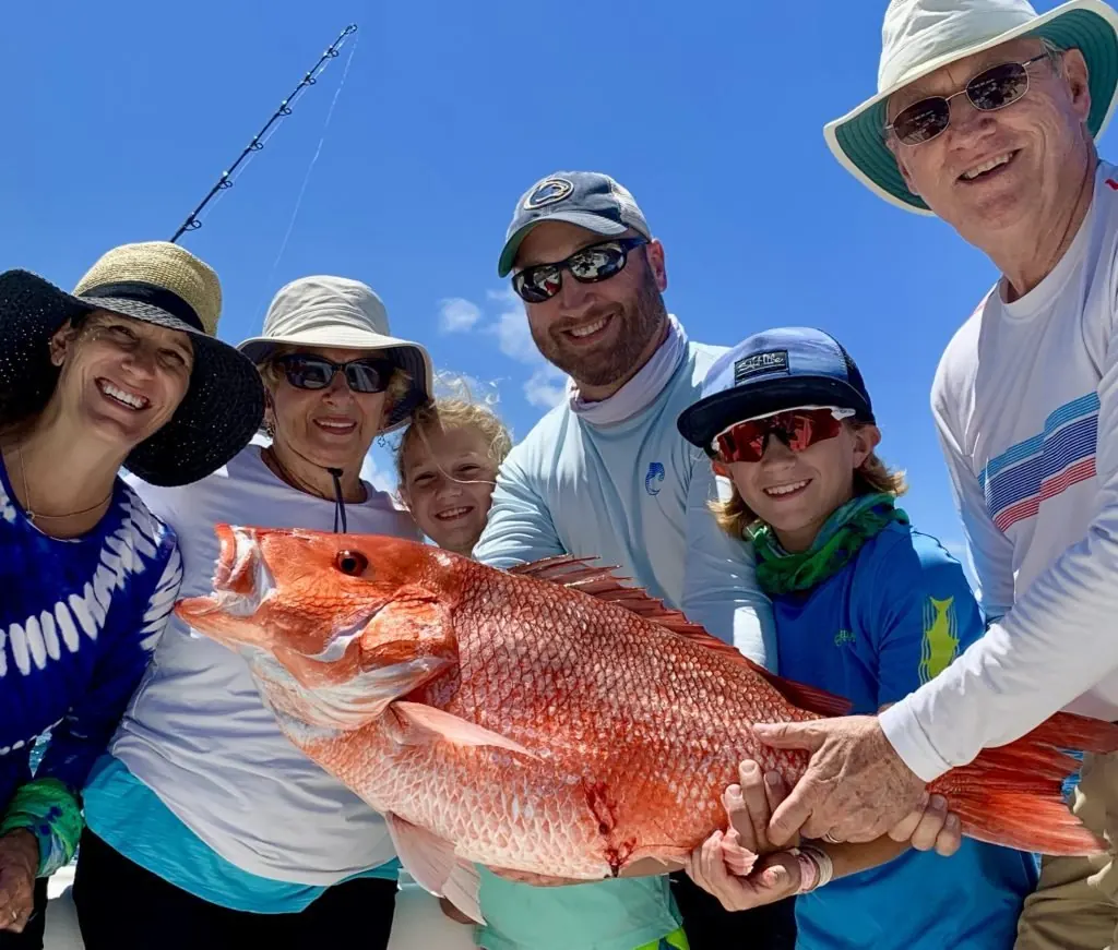 Family holding a red snapper caught on a fishing charter off Jaco, Costa Rica