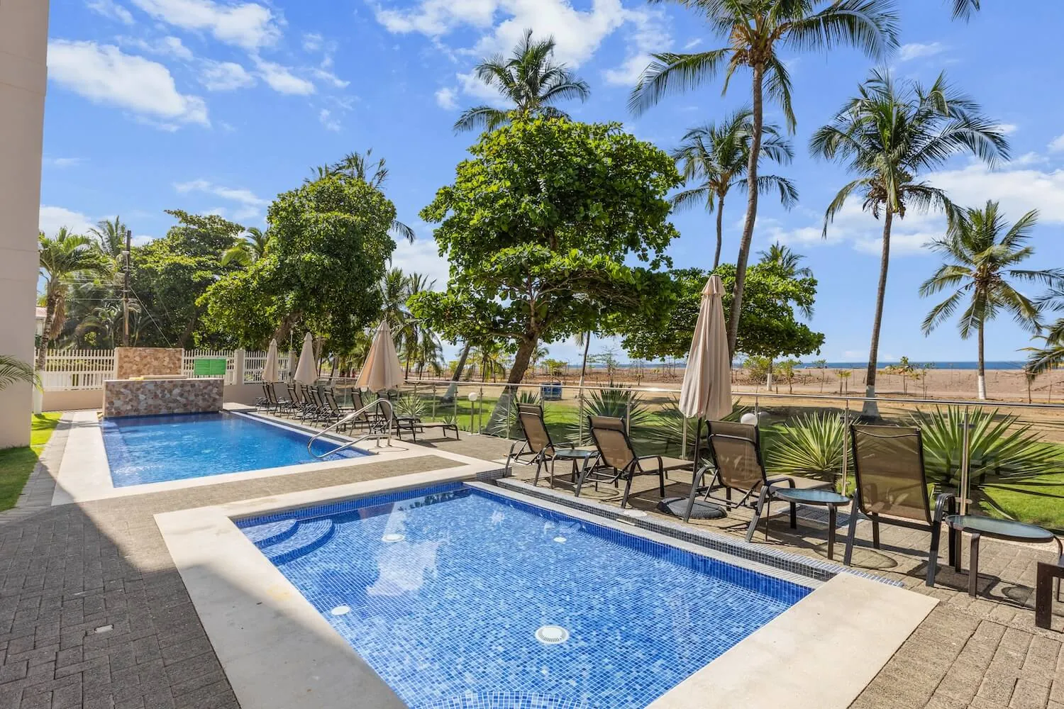 The Palms beachfront pool with lounge chairs a few steps from Jaco Beach
