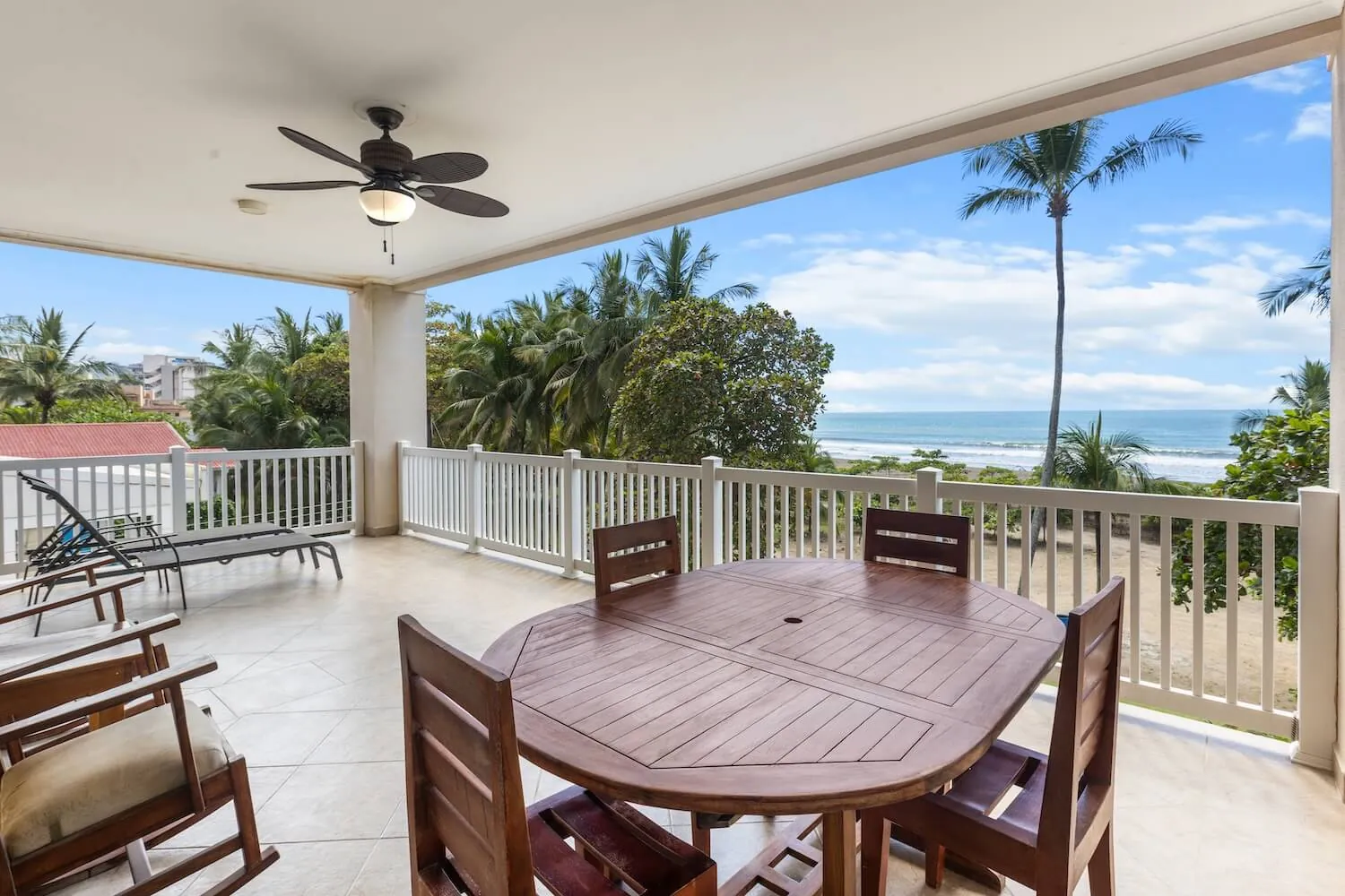 Balcony of The Palms 304 with wooden dining table and the ocean beyond the palms