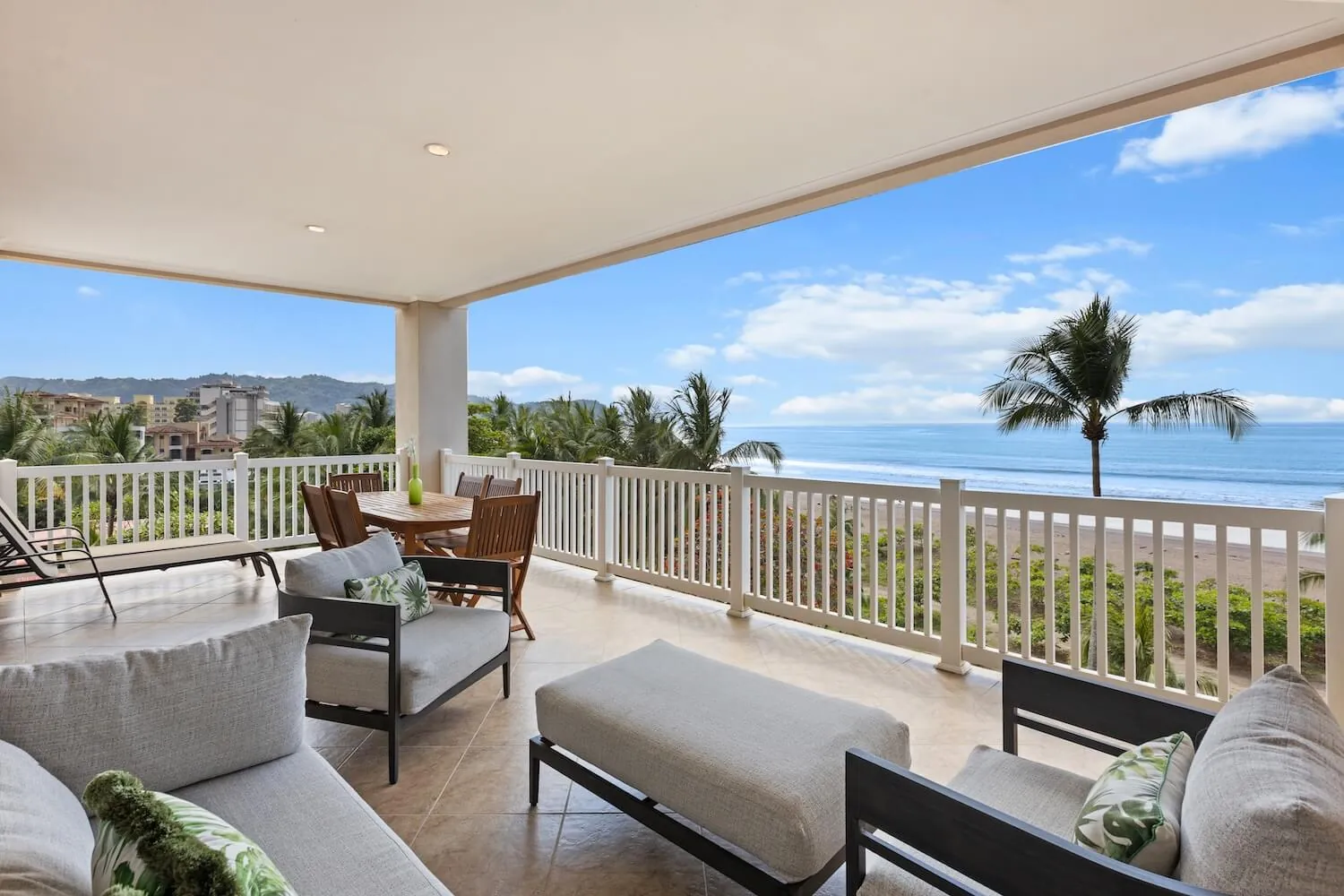 Balcony of The Palms 504 with lounge chairs and a view over the beach to Jaco town
