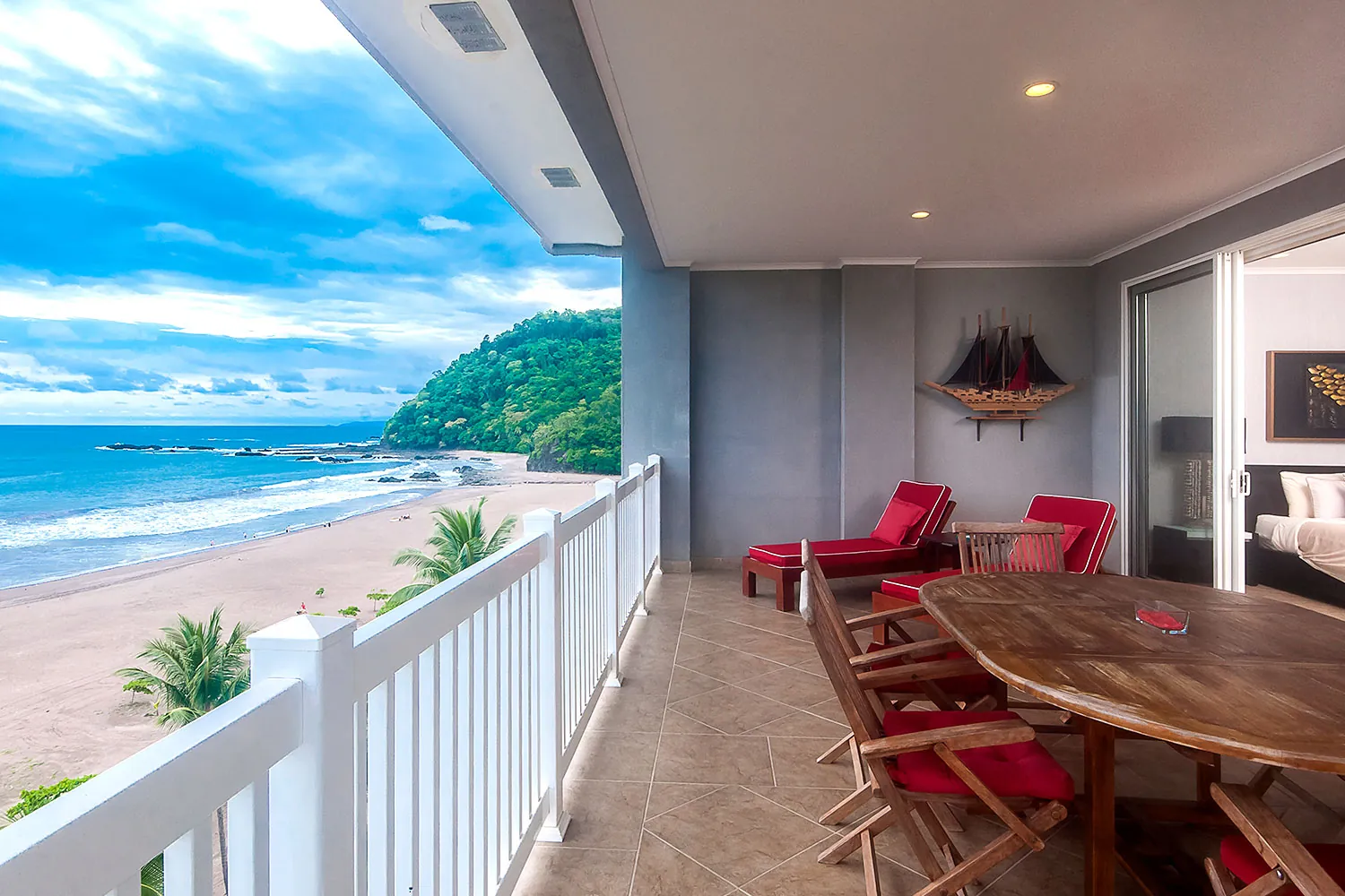 Balcony of The Palms 704 with red loungers and a view of Jaco Beach