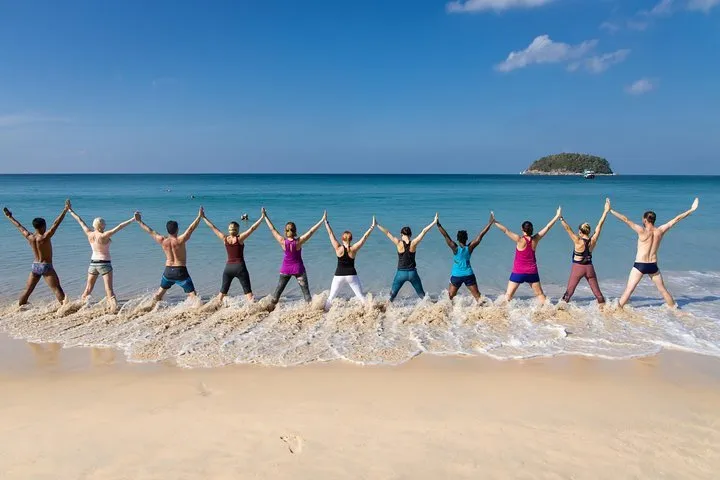 Wellness retreat group joining hands at the edge of the ocean on a Costa Rica beach